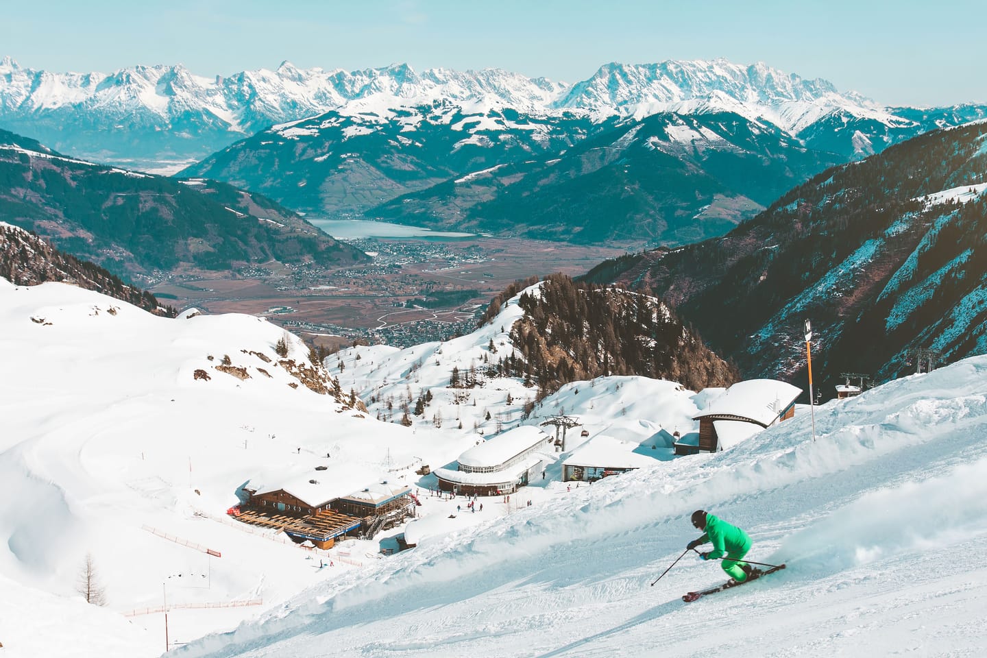 Skieur sur une piste au soleil, palace en contrebas.