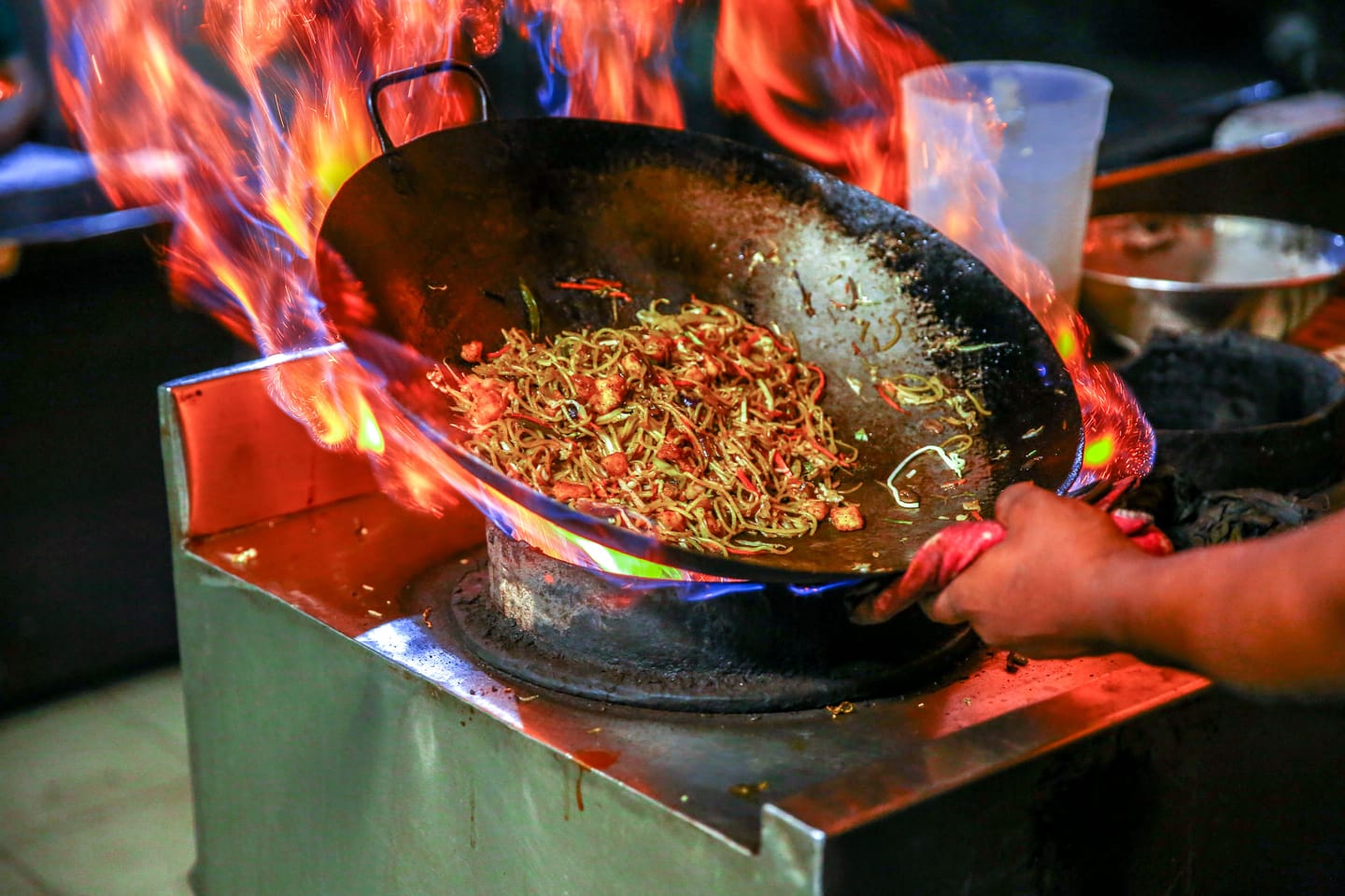 Les tables partagées d'un hawker centre, woks en pleine action.