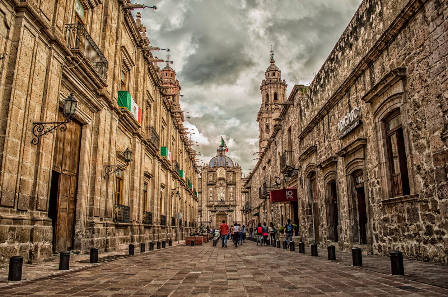 Une rue de pierre d'une ville coloniale mexicaine, cathédrale au fond.