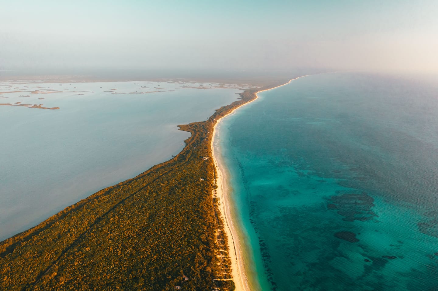 Une langue de sable entre le lagon et la mer turquoise, vue du ciel.