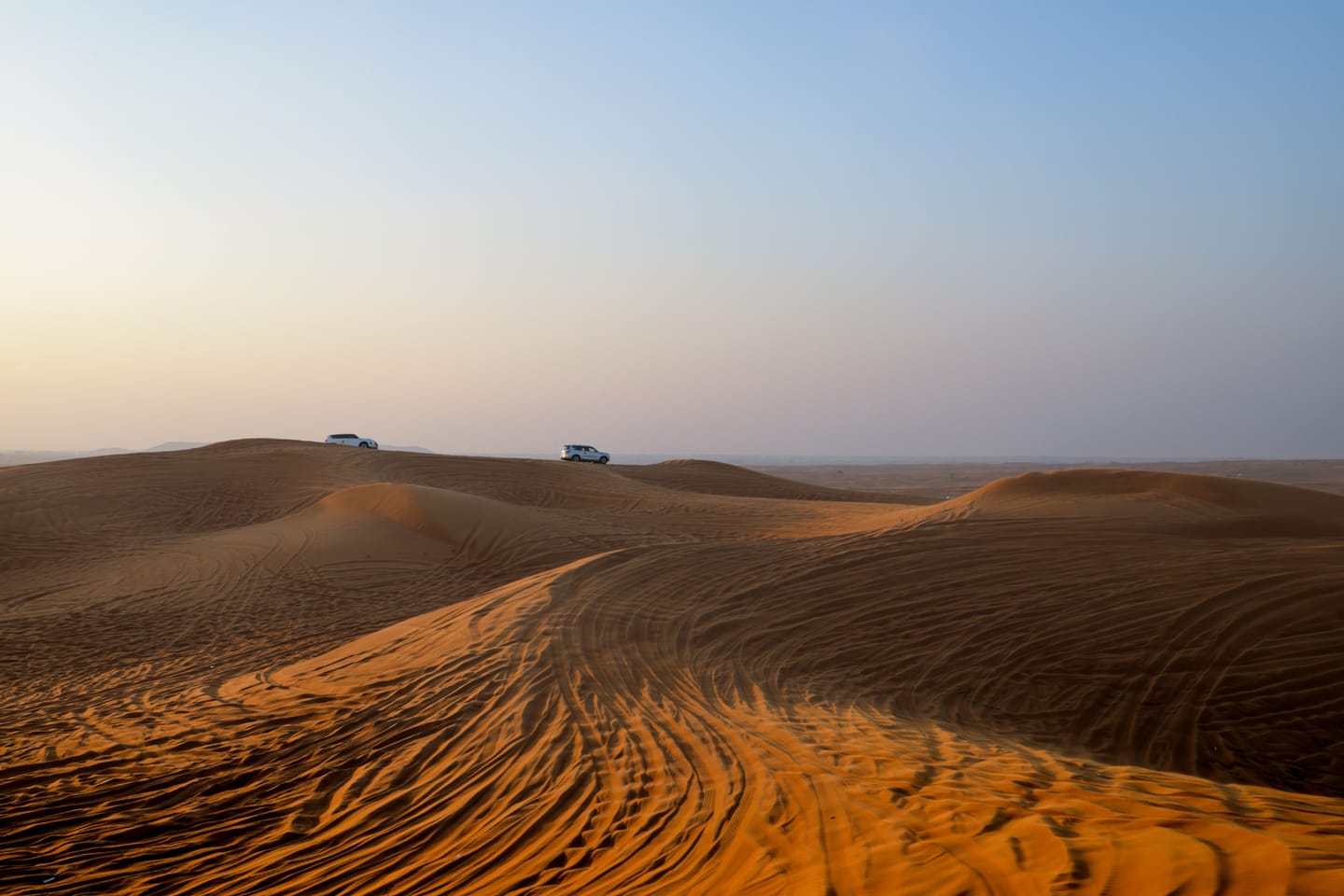 Desert dunes at dusk, a 4x4 in silhouette.
