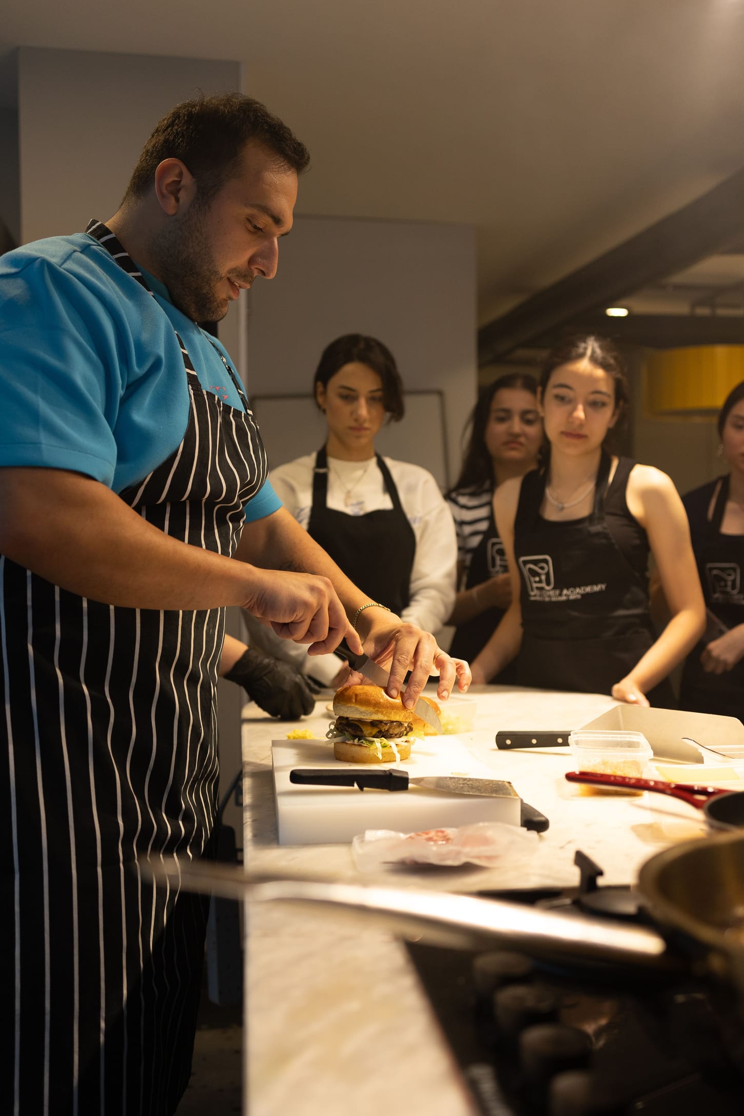 Un chef et de jeunes commis autour d'un plan de travail.